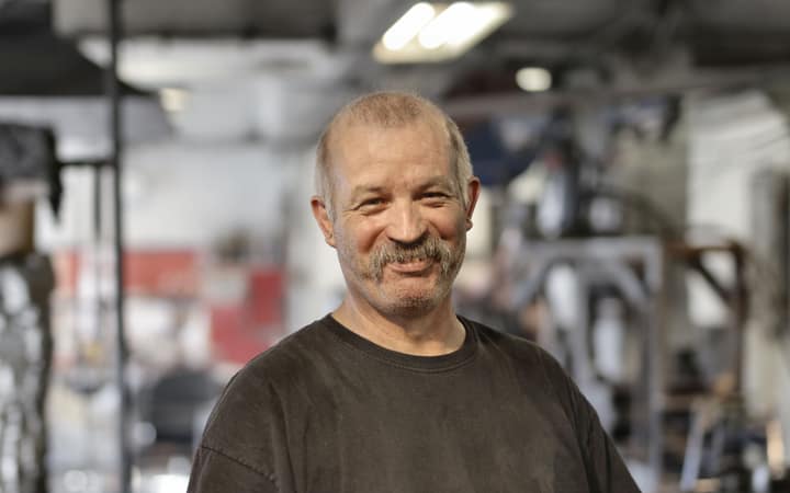 Profissional sorrindo em uma oficina metalúrgica