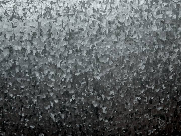 Close da superfície de uma chapa de aço galvanizado, com o padrão de cristais de zinco